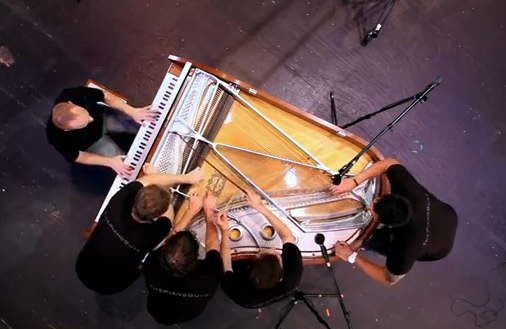 Cinco hombres tocando el piano