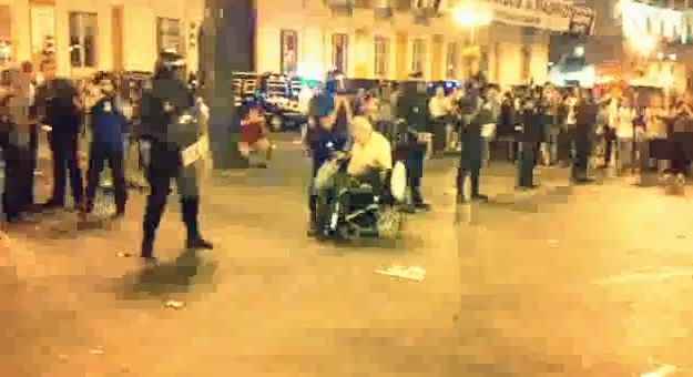 Un hombre en silla de ruedas hace un slalom entre los antidisturbios de la Puerta del Sol