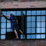Una abuela limpiando la ventana de su casa a fondo