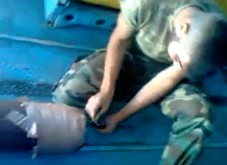 Un soldado sirio a bordo de un helicóptero enciende la mecha de una bomba casera y la lanza a un pueblo
