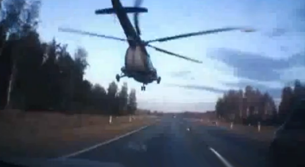 Un helicóptero militar Mi-8 adelanta a una gran cantidad de coches en una autovía rusa