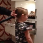 Un padre le hace una coleta a su hija con una aspiradora