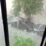 Un hombre intenta proteger su coche de una tormenta de granizo