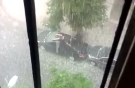 Un hombre intenta proteger su coche de una tormenta de granizo