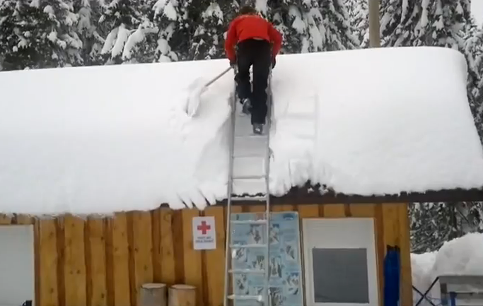 Mientras uno quita la nieve del tejado, los demás miran como casi se parte la crisma