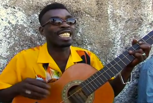 Brushy One String cantando 'Chicken In The Corn' acompañado de una guitarra de una sola cuerda