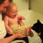 El bebé no puede aguantar la risa cuando el gato le lame los pies