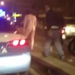 Un policía intenta meter en el coche a un hombre que camina desnudo por una calle de Nápoles