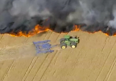 Un agricultor hace un cortafuegos con su tractor