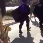 Un saxofonista pone música de acompañamiento a varios policías antidisturbios