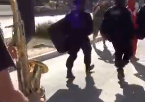 Un saxofonista pone música de acompañamiento a varios policías antidisturbios