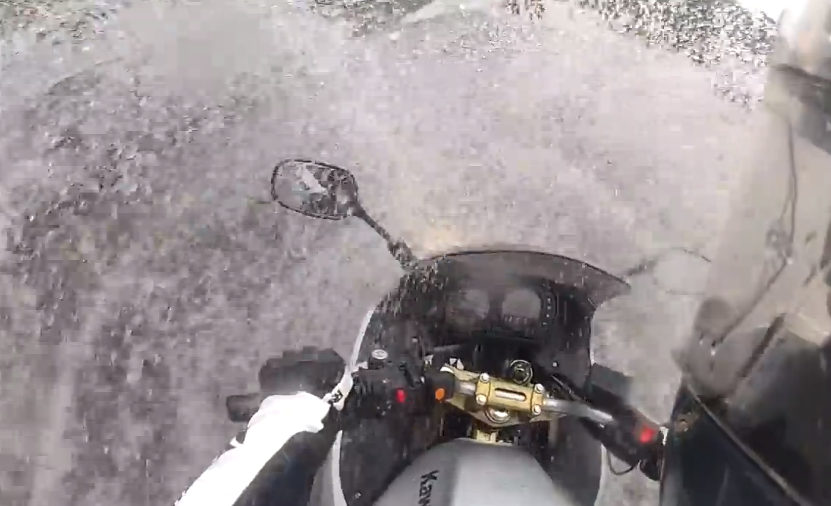 Motorista en una Kawasaki ER6 atravesando una autopista inundada