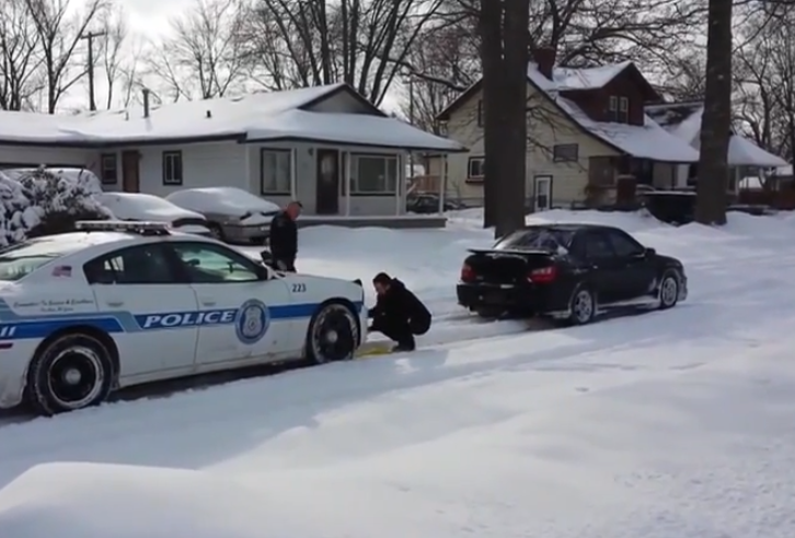 Conductor ayudando a un coche de policía atrapado en la nieve