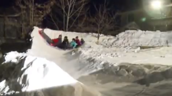 Una familia se hace un tobogán de hielo en el patio trasero de la casa