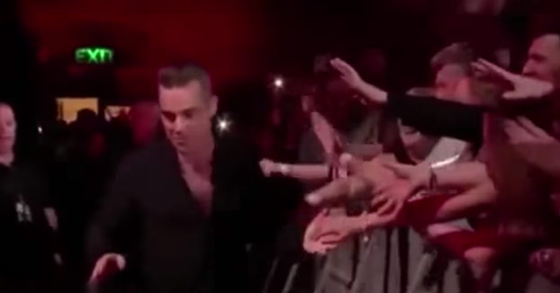 Robbie Williams se limpia las manos con desinfectante después de tocar a sus fans