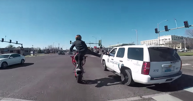 Policía chocándole las cinco a un motorista mientras hace un caballito