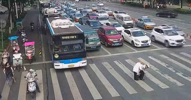 Un policía chino ayuda a un anciano a cruzar la calle montándolo en su espalda