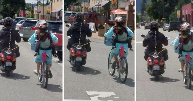 Madre llevando a su hijo en bici en una mochila mientras una scooter tira de ella con una cuerda