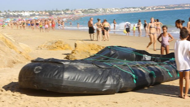 Una patera de inmigrantes desembarca en una playa abarrotada de Chiclana