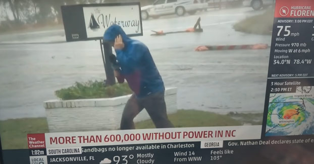 Un reportero lucha en directo contra el viento huracanado y entran en plano dos peatones tan campantes