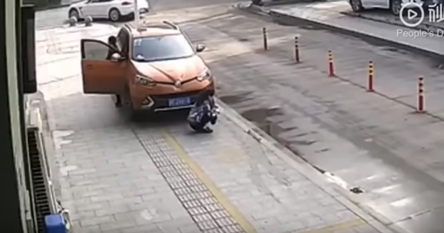 Una mujer se agacha delante de un coche para mirar su teléfono, el conductor arranca y la atropella