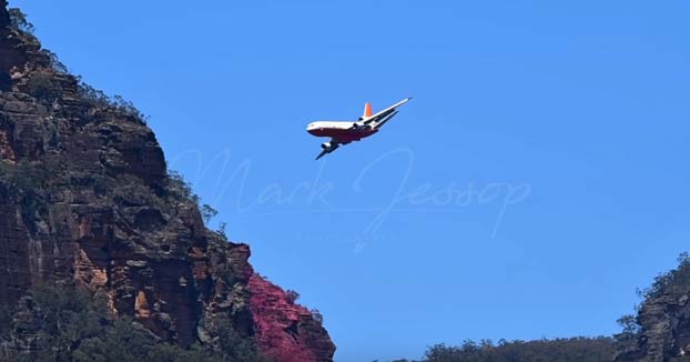 Avión echando retardante de fuego sobre varios focos en un monte australiano