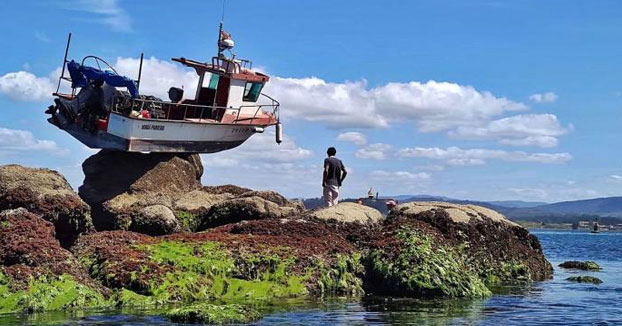 Un barco amanece suspendido sobre una roca de Punta Cabreira, en La Toja