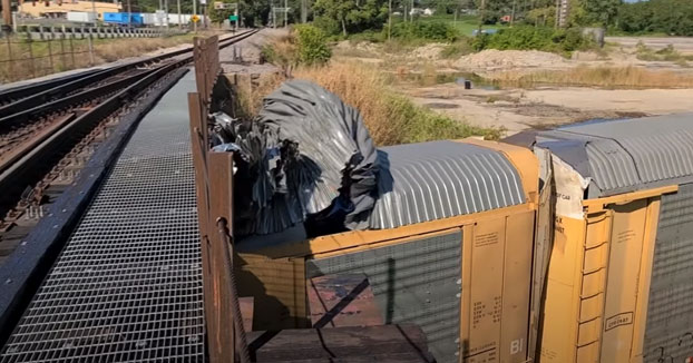 Tren pasa bajo un puente demasiado bajo y es afeitado, también los coches que transportaba