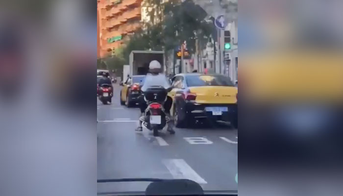 Un taxista tira de la moto a dos personas en Barcelona